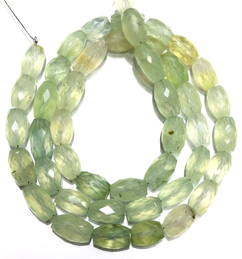 May include: A strand of light green faceted gemstone beads. The beads are oval shaped and have a translucent appearance.