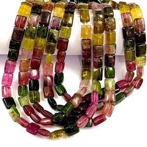 Puede incluir: Una hebra de cuentas de piedras preciosas cuadradas multicolores. Las cuentas son una mezcla de rosa, verde y amarillo.