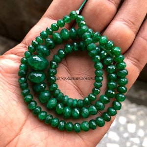 Puede incluir: Una hebra de cuentas de piedras preciosas facetadas de color verde esmeralda. Las cuentas son redondas y tienen un acabado liso y pulido. Las cuentas están enhebradas en un hilo transparente y tienen un diámetro de aproximadamente 6 mm. Las cuentas están dispuestas en un patrón suelto y fluido. Las cuentas son de un color verde vibrante y tienen un ligero brillo. Las cuentas son perfectas para hacer joyas u otras manualidades.