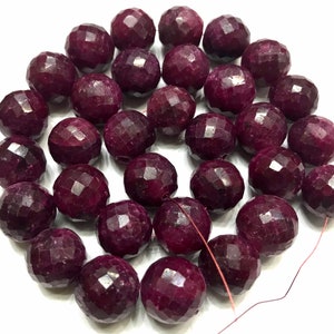 Puede incluir: Una hebra de cuentas de piedras preciosas facetadas de color rojo intenso. Las cuentas son redondas y tienen un acabado pulido. Las cuentas están enhebradas en un alambre fino.