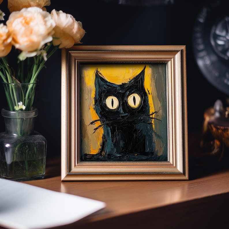 May include: A framed painting of a black cat with large yellow eyes. The cat is painted in a stylized, almost cartoonish style, with thick black lines and bright colors. The background is a yellow and green abstract design.