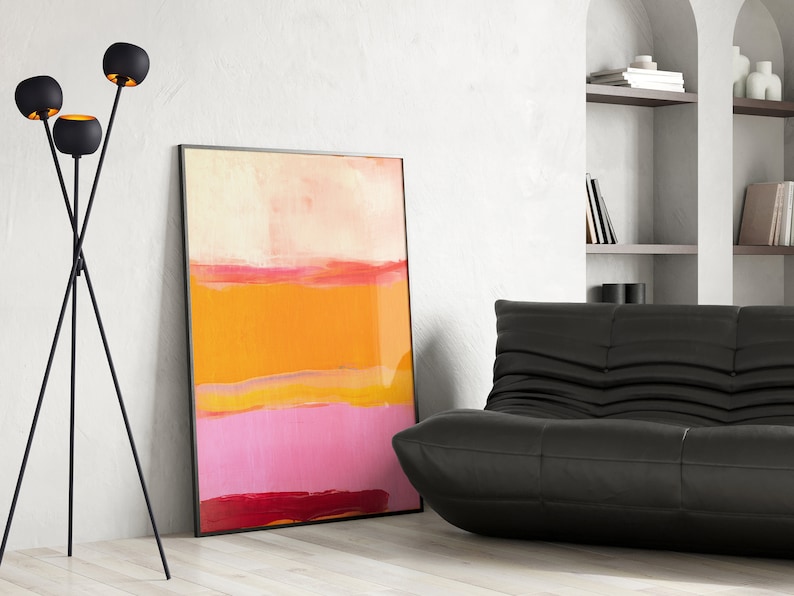 Puede incluir: Una l&aacute;mpara de pie de tr&iacute;pode negra con tres luminarias redondas de color dorado. La l&aacute;mpara est&aacute; en una sala de estar con un sof&aacute; de cuero negro y una pintura abstracta con tonos naranja, rosa y rojo.