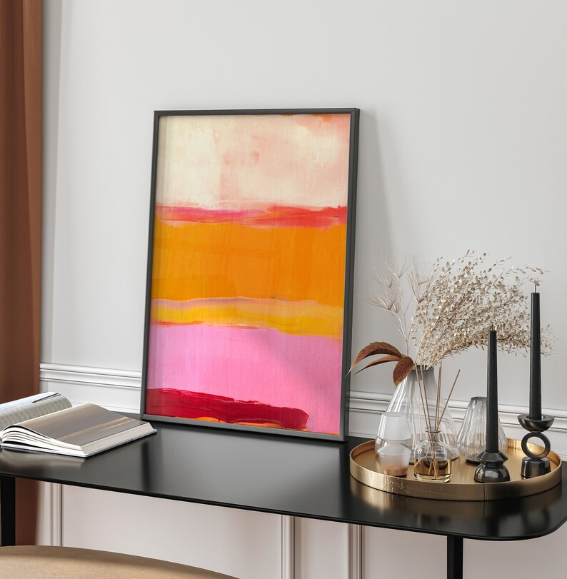 Puede incluir: Impresi&oacute;n de arte abstracto en un marco negro con un esquema de color rosa, naranja y amarillo. La impresi&oacute;n est&aacute; colgada en una pared blanca sobre una mesa negra con art&iacute;culos decorativos.