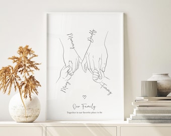 May include: A framed black and white line art print. The artwork shows four hands holding each other, with the words "Mommy," "Daddy," "Mary," and "Timmy" written above each hand. The text "Our Family" and "Together is our favourite place to be" are also included.