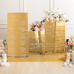 May include: Gold mirror acrylic wedding signage with the text "Find Your Seat", "The Best Day Ever", "Nicholas Loraine", "Manthan & Polina", "7:00 PM Ceremony", "8:00 PM Cocktail Hour", "9:00 PM Dinner", "10:00 PM Reception", and "12.18.2021 Highland Indiana".