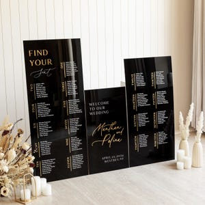 May include: Black acrylic wedding seating chart with gold lettering. The chart is divided into sections labeled with numbers one through nineteen. Each section lists names of guests. The chart also includes the text "Find Your Seat", "Welcome to Our Wedding", "Morthen and  Peifine", "April 25, 2024", and "Westbey, NY".