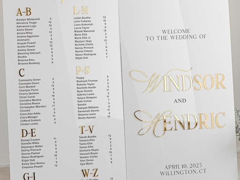 K&ouml;nnte beinhalten: Ein wei&szlig;er Hochzeitssitzplan mit goldenen Buchstaben. Der Plan listet die Namen der G&auml;ste in alphabetischer Reihenfolge auf. Die Namen sind in Abschnitte unterteilt, die mit A-B, L-N, P-S, T-V und W-Z gekennzeichnet sind. Der Plan enth&auml;lt auch den Text "Willkommen zur Hochzeit von Windsor und Hendric" sowie das Datum "10. April 2025" und den Ort "Willington, CT".