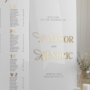 K&ouml;nnte beinhalten: Ein wei&szlig;es Hochzeitsschild mit goldenen Buchstaben. Das Schild lautet "Willkommen zur Hochzeit von Windsor und Kendric, 10. April 2025, Willington, CT".