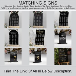 May include: A set of black acrylic wedding signs with gold lettering. The signs include a welcome sign, seating chart, table numbers, bar sign, and unplugged ceremony sign. The signs are all in a modern, minimalist style.