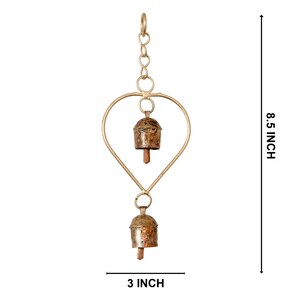 May include: A decorative wind chime featuring two small bells suspended within a gold-colored heart-shaped frame. The chime is 8.5 inches long and 3 inches wide. The bells have a rustic, aged appearance, and the overall design is simple and elegant.