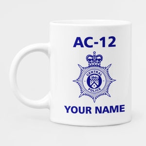 May include: White ceramic mug with a blue graphic of a police badge with a crown and the text "CENTRAL POLICE" and the text "AC-12" above the badge and the text "YOUR NAME" below the badge.