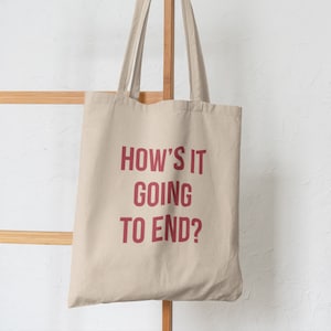 May include: A beige tote bag with red text that reads "How's it going to end?"