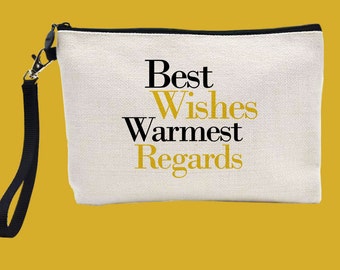 May include: A white canvas zippered pouch with a black zipper and a black strap. The pouch has the text "Best Wishes Warmest Regards" printed in black and gold letters.