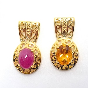 May include: Two gold pendants with ornate filigree designs. One pendant features a pink oval gemstone, while the other has a yellow oval gemstone.