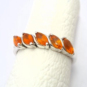 May include: A silver ring with six orange marquise-shaped gemstones set in a row.