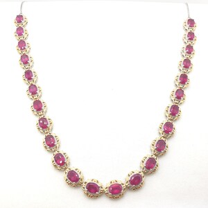 May include: A gold and silver necklace with oval-shaped red gemstones set in a delicate floral design.