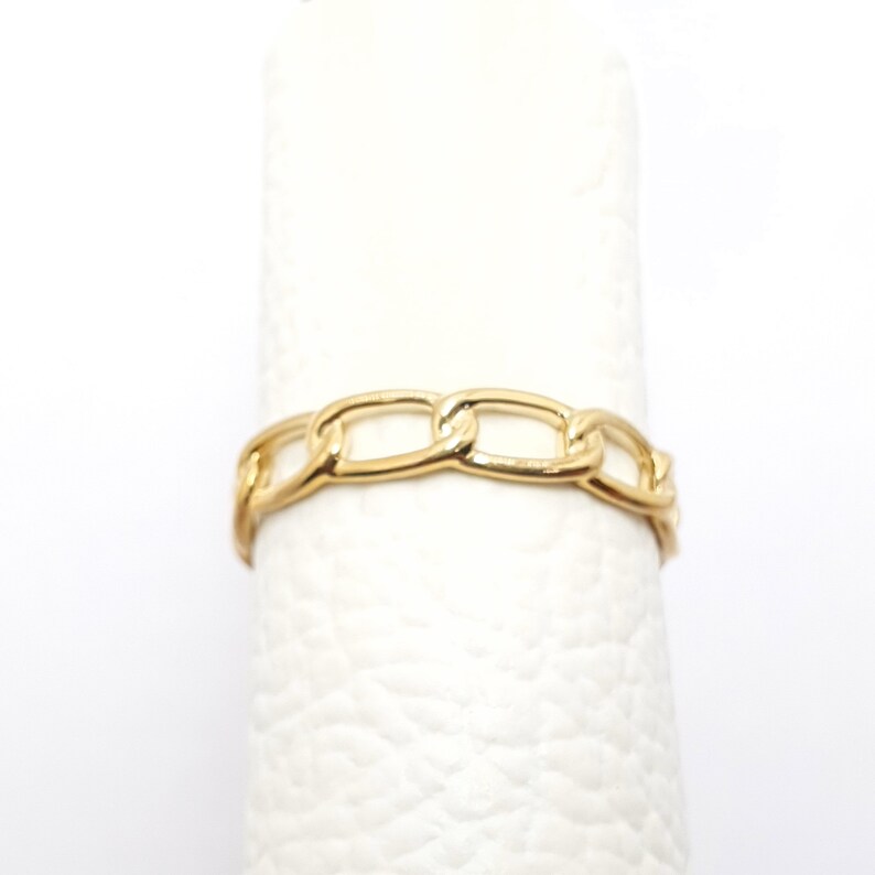 K&ouml;nnte beinhalten: Ein goldener Kettenring mit schlichtem Design. Der Ring besteht aus einer dicken, massiven Kette.
