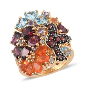 May include: A gold ring with a colorful gemstone design. The ring features a bird shape with red, orange, blue, and purple gemstones. The ring is set with a variety of gemstones, including garnets, opals, and topaz.