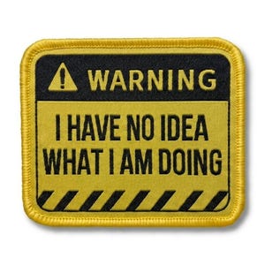 May include: A rectangular embroidered patch with a yellow border. The top section is black with a yellow warning triangle and the word WARNING. The lower yellow section features the black text I HAVE NO IDEA WHAT I AM DOING above black diagonal stripes.