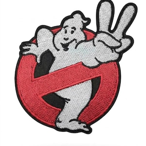 Puede incluir: Un parche bordado que presenta un personaje fantasma blanco con una expresión sonriente, haciendo un signo de paz con una mano. El fantasma está colocado frente a un emblema circular rojo con un borde negro grueso y una barra diagonal roja.