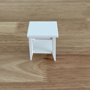 a small white table sitting on top of a wooden floor