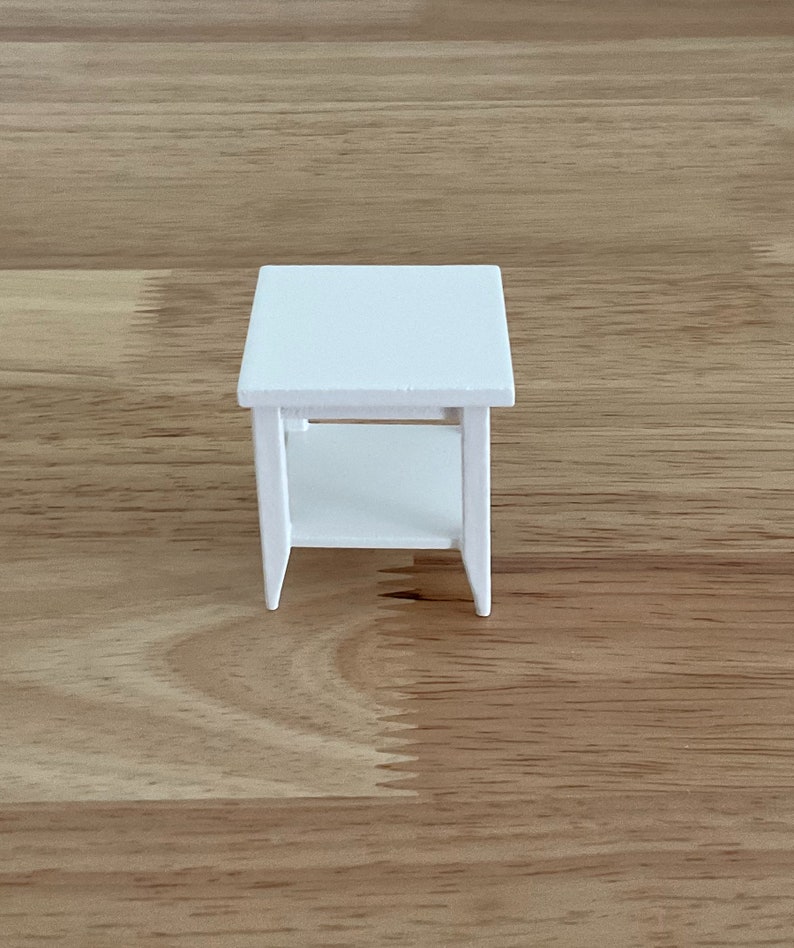 a small white table sitting on top of a wooden floor