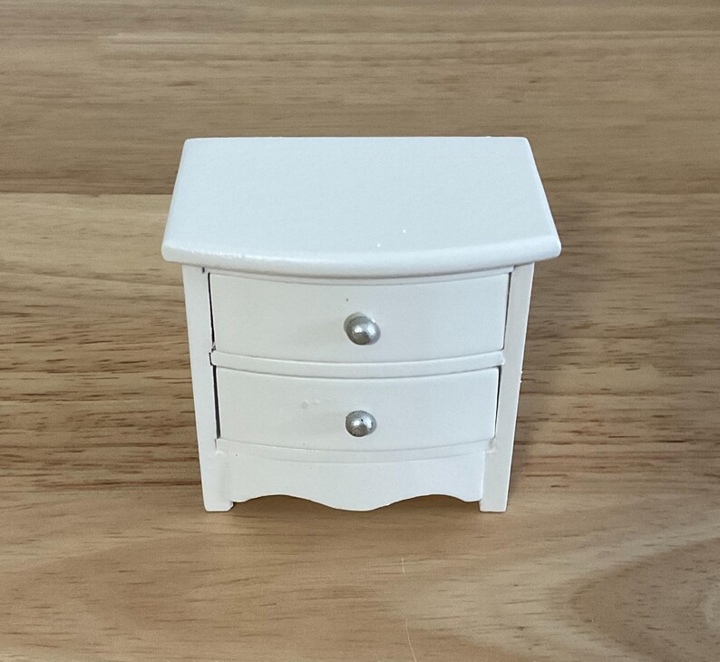 a small white table with a drawer on top of it