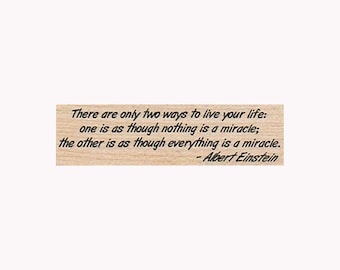 May include: A wooden stamp with a quote by Albert Einstein: "There are only two ways to live your life: one is as though nothing is a miracle; the other is as though everything is a miracle."