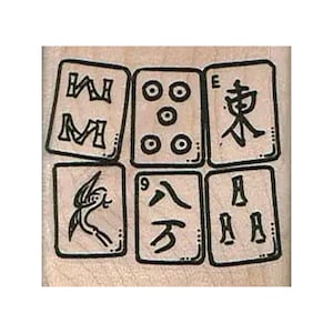 May include: A light-colored wooden rubber stamp featuring a grid of six Mahjong tiles. The tiles display black ink illustrations including the East wind character, a five-dot pattern, the number nine character, a bird, and other symbols.