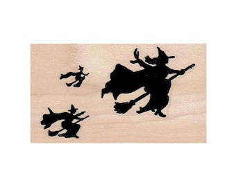 Könnte beinhalten: Ein auf Holz montierter Gummistempel mit drei schwarzen Silhouetten von Hexen, die auf Besen fliegen.
