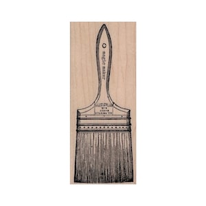 May include: A wooden stamp with a black and white illustration of a paint brush. The stamp is labeled "magic maker".