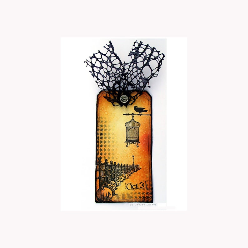 May include: A Halloween-themed tag with a black lace overlay. The tag features a vintage-style illustration of a birdcage, a crow, and a fence with skulls. The text "Oct. 31" is printed on the tag.
