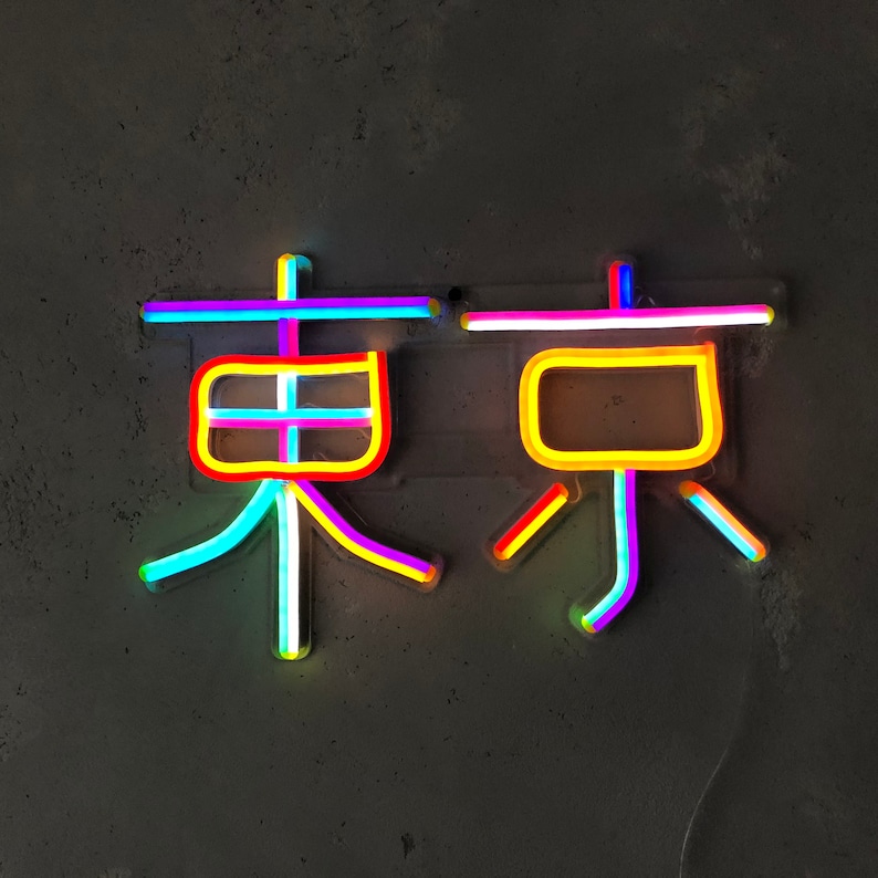 May include: Neon sign with the word "Tokyo" in Japanese characters. The sign is made of multiple colors, including pink, yellow, blue, and white.