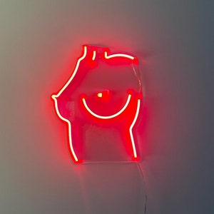 May include: A red neon sign in the shape of a smiling face with a simple outline. The sign is mounted on a white wall.