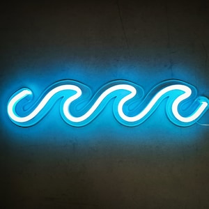 Puede incluir: Un letrero de neón azul con forma de ola. El letrero está encendido y brilla sobre un fondo oscuro.