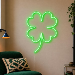 May include: A bright green neon sign shaped like a four-leaf clover. The light is mounted on a wall and features a continuous glowing outline of the clover leaves and a single stem extending downward, creating a vibrant and luminous display.