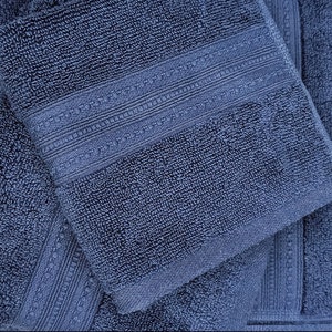 May include: Three blue bath towels folded on top of each other. The top towel has a decorative border.