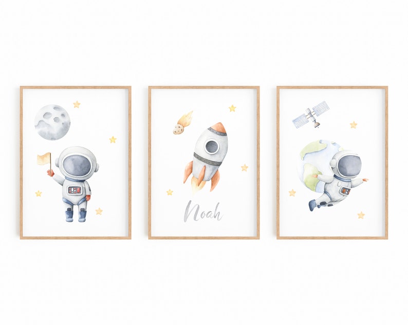 以下が含まれることがあります： 宇宙をテーマにしたイラストが描かれた、額入りの水彩画プリント3枚セットです。月面に着陸した宇宙飛行士、名前「Noah」のロケット、地球を持つ宇宙飛行士が描かれています。各プリントは木製のフレームで、黄色の星のアクセントが付いています。