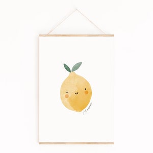 Puede incluir: Una impresi&oacute;n en acuarela de un lim&oacute;n sonriente con hojas verdes. La fruta amarilla tiene una carita feliz y el nombre "Malea" est&aacute; escrito en cursiva. La impresi&oacute;n se muestra en un marco de madera, colgada de una cuerda.