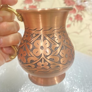 May include: A copper mug with a floral design and a brass handle. The mug is made of hammered copper and has a traditional Turkish design.