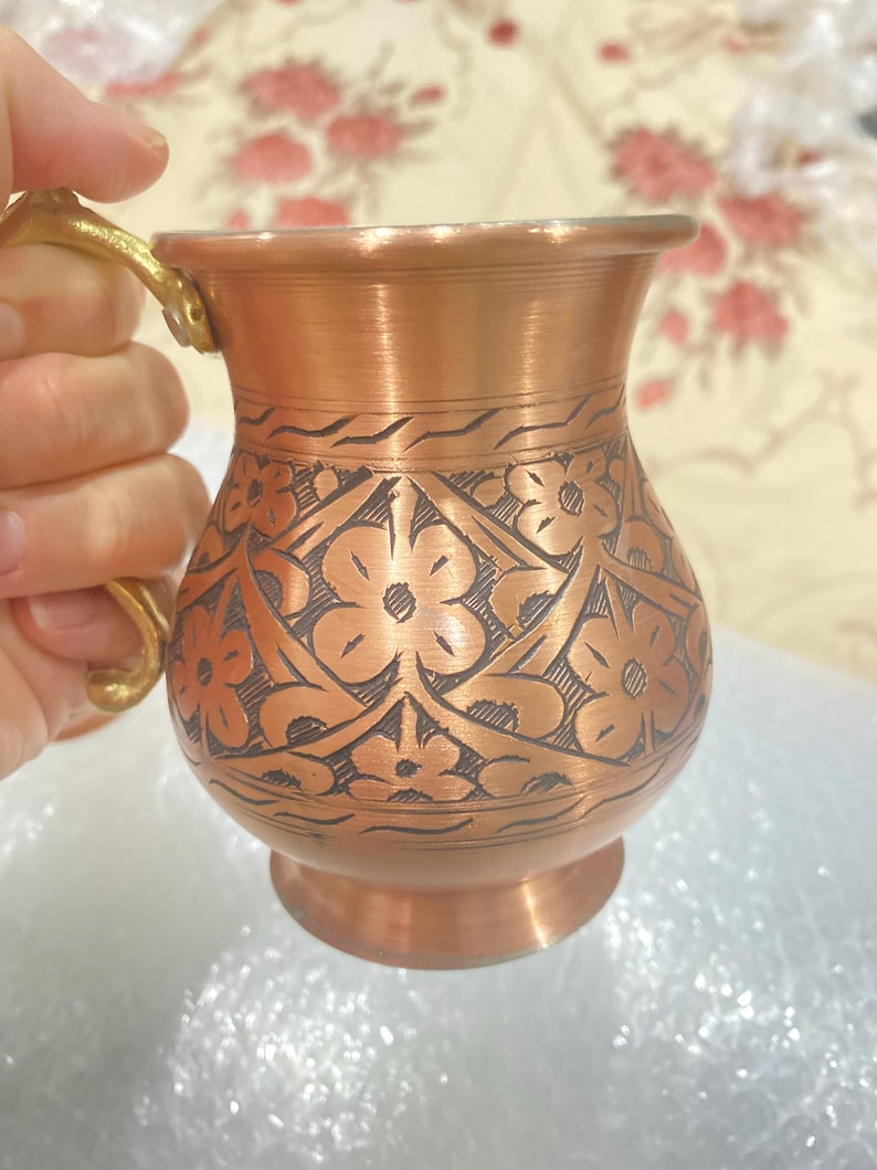 May include: A copper mug with a floral design and a brass handle. The mug is made of hammered copper and has a traditional Turkish design.