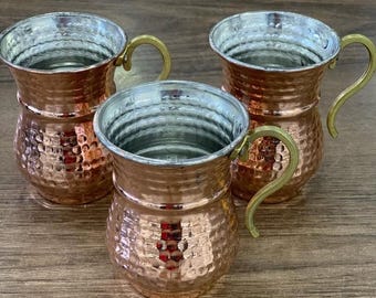 May include: Three hammered copper mugs with brass handles. The mugs have a traditional Turkish design and are perfect for serving beverages.