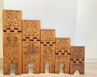 Op de afbeelding: Een set van zes houten boekenleggers met ingewikkelde gesneden ontwerpen. De boekenleggers zijn gestapeld in een aflopende maat, met de grootste aan de onderkant en de kleinste aan de bovenkant. De boekenleggers zijn gemaakt van lichtbruin hout en hebben een natuurlijke afwerking.