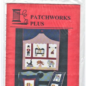 Könnte beinhalten: Ein rotes, weißes und blaues Patchwork-Quiltmuster mit einem Zirkuszelt mit verschiedenen Tieren und Artisten. Das Muster trägt den Titel "Under the Big Top Circus Fun for All Ages" und ist mit "PP-5" gekennzeichnet.