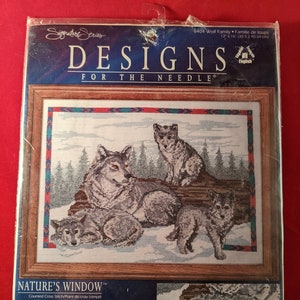 May include: A counted cross stitch pattern featuring a wolf family in a snowy forest setting. The pattern is titled "Nature's Window" and is 12 inches by 16 inches (30.5 cm x 40.64 cm).