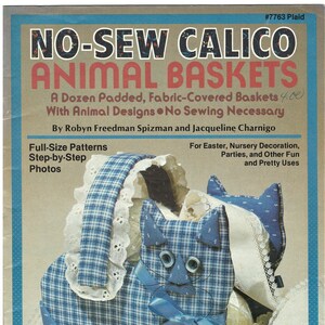 May include: A blue and white plaid calico cat-shaped basket with white lace trim and blue ribbon. The title "No-Sew Calico Animal Baskets" is printed on the cover. The text "A Dozen Padded, Fabric-Covered Baskets 4.00 With Animal Designs No Sewing Necessary" is printed on the cover. The text "Feline Fun Instructions on page 5" is printed on the bottom of the cover.