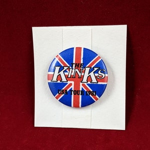 Könnte beinhalten: Ein blauer und roter Knopf mit einem Union-Jack-Design. Der Text "THE KINKS USA TOUR 1981" ist auf dem Knopf gedruckt.