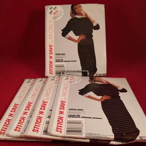 May include: A stack of six sewing patterns for a dress. The patterns are white with black text and a black and white striped dress illustration. The text on the patterns reads "Stitch 'N Save by McCall's" and "Petite-Able".