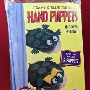 May include: A package of two turtle hand puppets. The puppets are green with yellow accents and have large eyes. The package says "Tommy & Tillie Turtle Hand Puppets" and "No Sewing Required!"  Each kit makes two puppets. A project by Creative Kits.