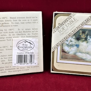 K&ouml;nnte beinhalten: Set mit vier wei&szlig;en Keramik-Untersetzern mit einem Bild von drei wei&szlig;en Katzen. Die Untersetzer sind in einer wei&szlig;en Schachtel verpackt, auf der vorne der Text "Top Table Tableware Collection Four Coasters" steht.
